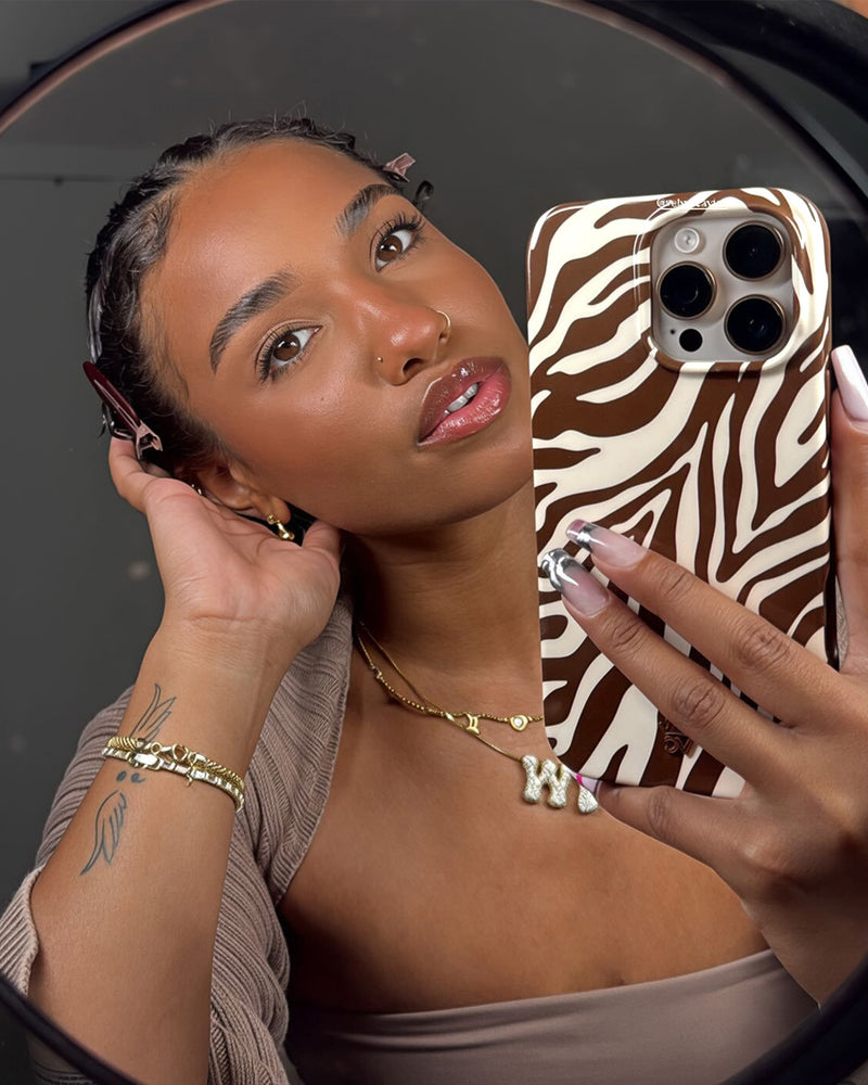 Woman holding zebra stripe phone case in brown and white animal print pattern