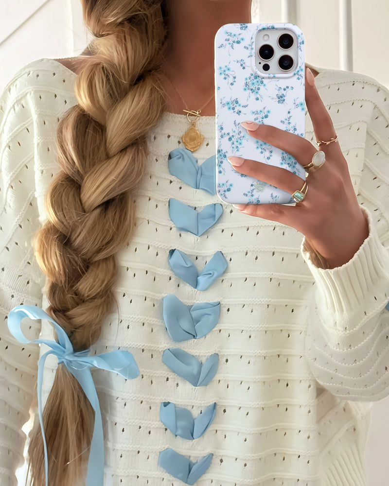 Blonde woman with braided hair holding blue phone case in white polka dot top